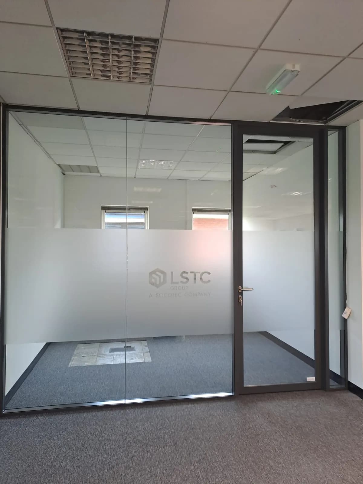 Full-height glazed partition with framed door and privacy band at Charlotte House in Derby