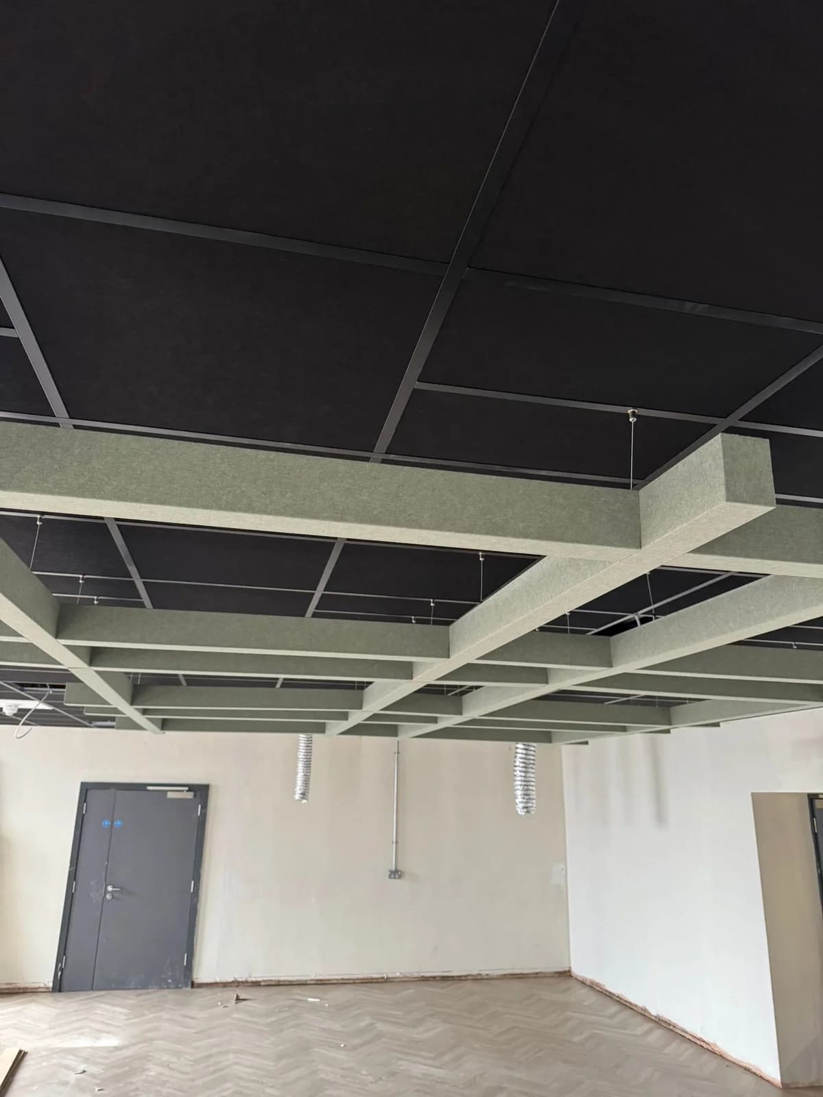 Installation stage showing white acoustic baffles against a black ceiling at Jubilee Campus