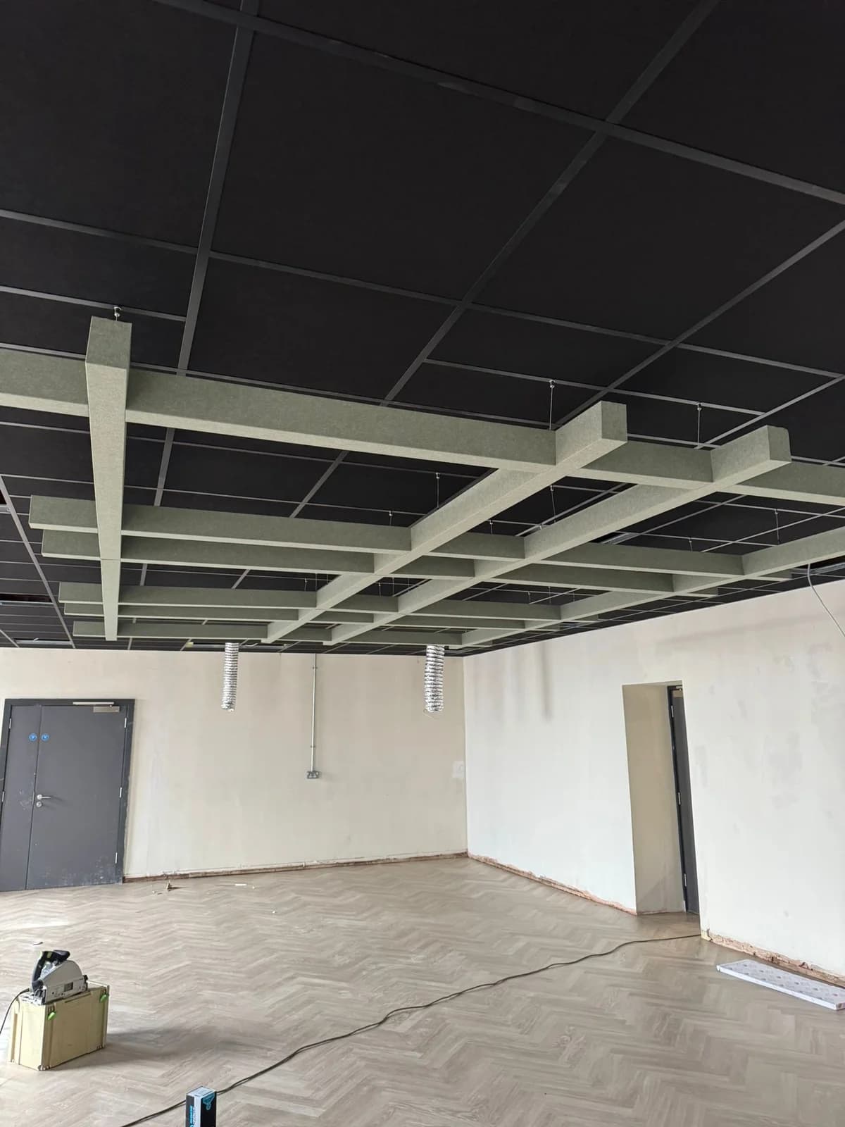 Black suspended ceiling and white hanging acoustic baffles in a Jubilee Campus room