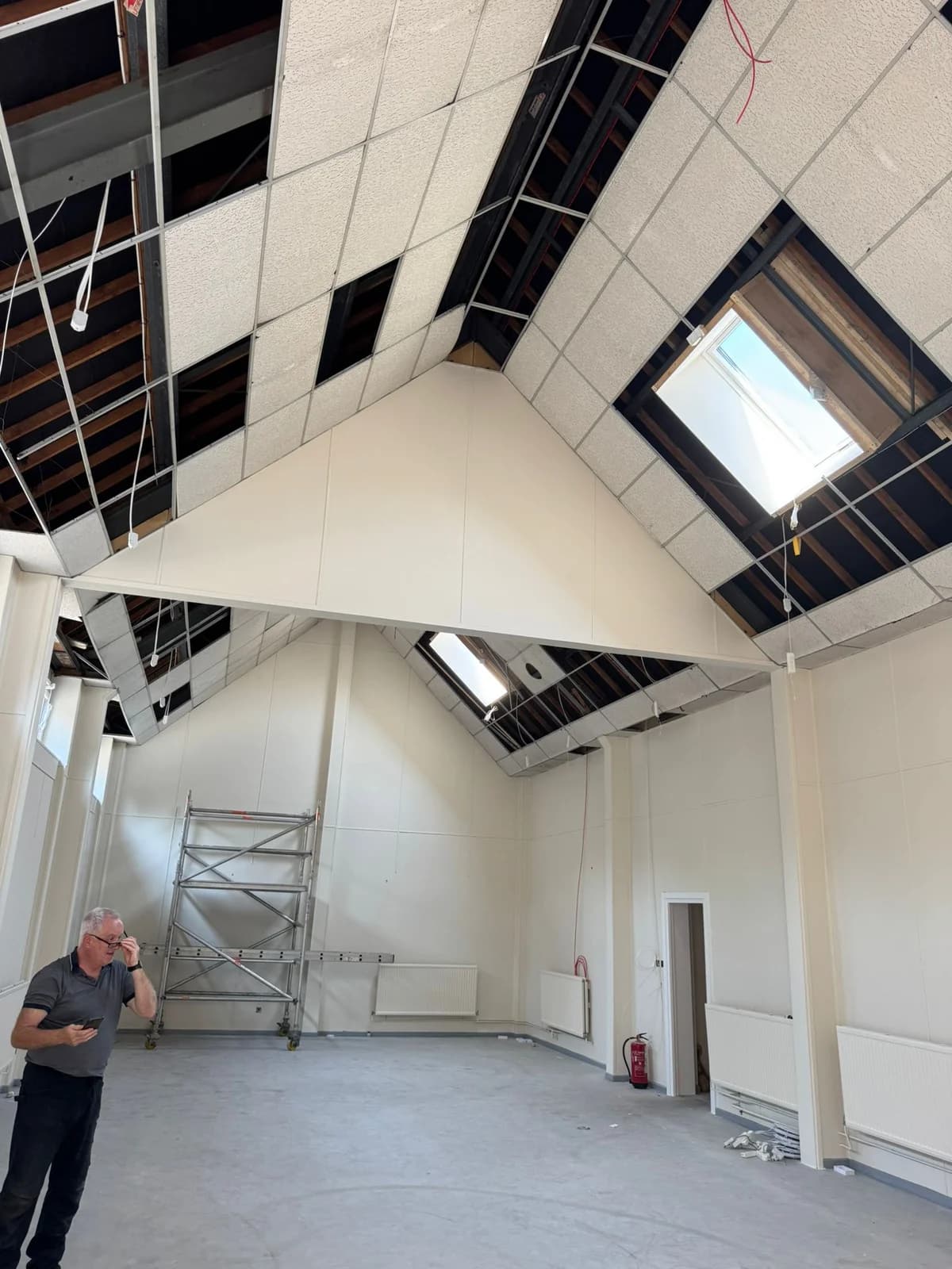 Before view of missing suspended ceiling tiles across the church roof pitch