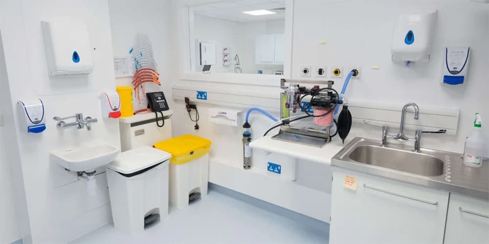 Clinical treatment room with hygienic white wall cladding, sinks and medical equipment